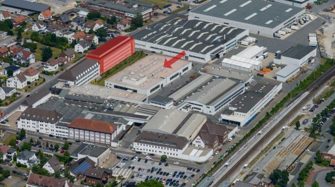 Das rot markierte Gebäude zeigt das geplante Forschungs- und Entwicklungszentrum, das entlang der Borriesstraße entstehen soll. Der Pfeil weist auf die Halle (hier noch mit der alten Lichtkuppel) für die neue Pressenanlage. Bild: Miele